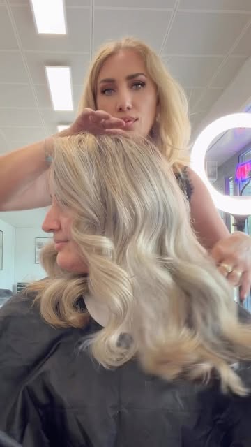 Coiffeuse stylt blondes Haar einer Kundin